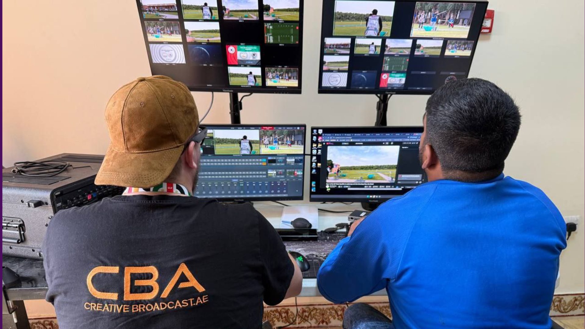 Two CBA operators at the vision mix desk, the programme and camera feeds on the multiviewer screens above them