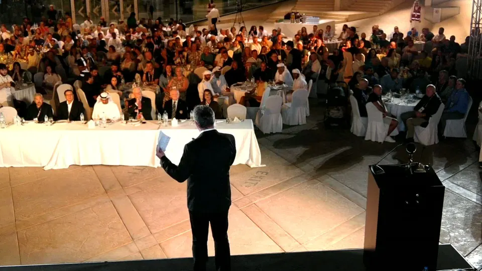 Camera one: a speaker at the front of the room addressing seated guests at an outdoor awards gala we broadcast in December 2025